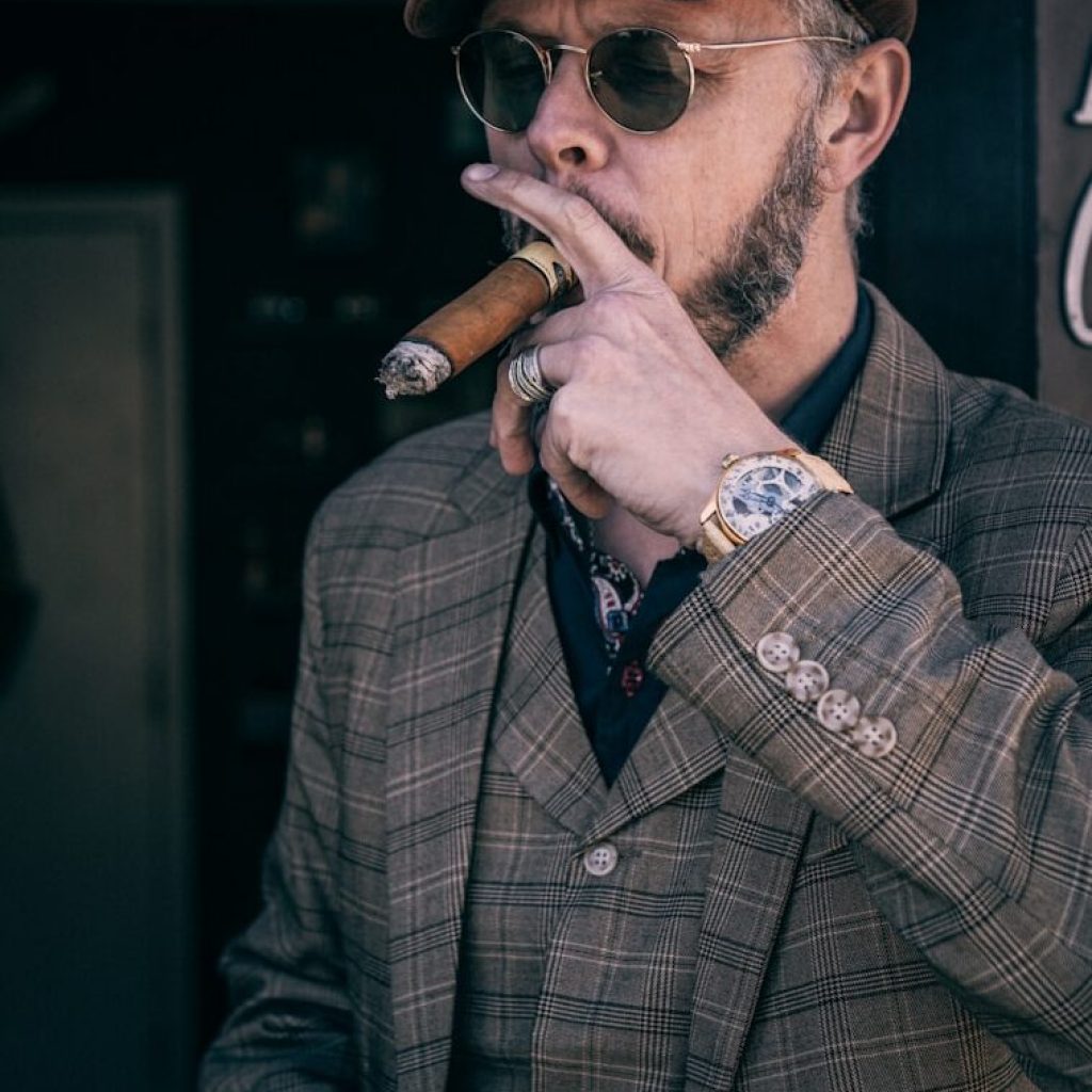 man in brown and black plaid coat smoking cigarette